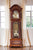 Orologio a pendolo in legno con frontali decorati, vista sul pendolo e sul meccanismo attraverso il vetro