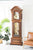 Orologio a pendolo in cassa di legno marrone con fronte goffrata, finestra in vetro e pesi a vista.