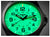 Orologio da uomo in primo piano: quadrante verde luminoso con lancette e numeri.