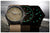 Due orologi da polso uno accanto all'altro, cinturini in tessuto marrone, quadranti con indici luminescenti verdi