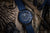 Herrenarmbanduhr mit blauem Zifferblatt, blauem Textilband und grün leuchtenden Markierungen