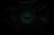 Herrenarmbanduhr bei gedimmtem Licht mit grün leuchtendem Zifferblatt und blauem Band