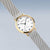 Damenuhr mit Maschenarmband, goldfarbener Lünette und weißem Zifferblatt mit schwarzen Zeigern