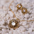 "Collana color oro con pietra di madreperla rotonda in cornice floreale a forma di stella"