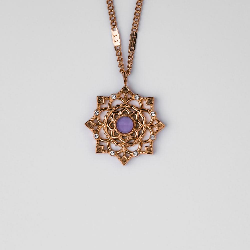 "Collana color oro con ciondolo rotondo e pietra viola in una cornice ornamentale"