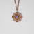 "Collana color oro con ciondolo rotondo e pietra viola in una cornice ornamentale"