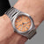 Herrenarmbanduhr am Handgelenk mit orangefarbenem Zifferblatt und Metallband
