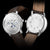 Alt text: Orologio Naos con quadrante a fasi lunari, cassa in acciaio inossidabile e cinturino in pelle marrone.