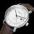 Orologio da uomo in primo piano: quadrante bianco con accenti verdi e cinturino in pelle marrone