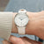 Orologio da donna al polso: cinturino in pelle beige, cassa argentata, quadrante bianco, lancette blu