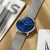 Orologio da uomo con quadrante blu su bracciale in rete metallica, vista obliqua