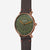 Sedia Naos X con braccioli, edizione 1905, finitura verde scuro e bronzo, seduta vintage color moka, vista a 45 gradi con sfondo grigio.