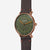 Orologio STERNGLAS Naos XL Edition 1905 verde scuro e bronzo con cinturino Vintage 20 mokka, vista a 45 gradi su sfondo grigio.