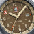 Dettaglio del quadrante di un orologio sportivo: display beige, lancette argentate, finestra della data a ore 31