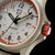 Quadrante di orologio da uomo in primo piano con finestra della data e pulsante rosso sul lato