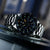 Herrenarmbanduhr mit schwarzem Zifferblatt, Leuchtzeigern und Edelstahl-Lünette im Detail