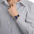 Orologio unisex al polso, quadrante blu, cassa argento, cinturino in tessuto blu scuro.