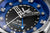 Primo piano: orologio da uomo con quadrante blu, lancette grandi e indici argentati.