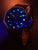 Orologio da uomo con cinturino in pelle marrone; quadrante blu con indici luminescenti verdi.