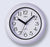 Runde Wanduhr mit hellem grauem Gehäuse, weißem Ziffernblatt und schwarzen Zeigern