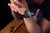 Herrenarmbanduhr am Handgelenk mit schwarzem Band und buntem, leuchtendem Zifferblatt