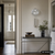Silberne Wanduhr mit rundem Zifferblatt und Metallpendel mit Kettenpendeln