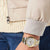 Am Handgelenk getragene Herrenarmbanduhr mit weißem Zifferblatt und Gold/Silber-Stahlband