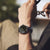 Orologio da uomo al polso con quadrante nero e cinturino in pelle marrone scuro