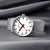 Mondaine Herrenuhr auf silbernem Maschenarmband, weißes Zifferblatt mit roten Zeigern