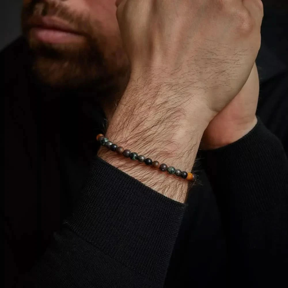 Armband mit dunklen Edelsteinperlen und grauem Edelstahlverschluss am Handgelenk