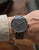Orologio da uomo al polso con cinturino in pelle marrone e quadrante nero