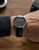 Orologio da uomo al polso con cinturino in pelle nera e quadrante scuro