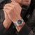 Herrenarmbanduhr am Handgelenk, Edelstahlband und schwarzes Zifferblatt mit Carbon-Optik