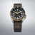 Orologio da uomo con quadrante nero, lunetta color oro e cinturino in pelle marrone.