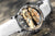 Primo piano di un orologio con movimento color oro e indici argentati sul quadrante