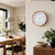 Orologio da parete con cornice effetto legno e quadrante bianco appeso al muro