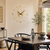 Wanduhr an der Wand mit rundem goldfarbenem Ziffernblatt, schwarzen Zeigern und Stäben