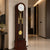 Orologio a pendolo con cassa in legno scuro, quadrante bianco e pendolo dorato in vetro