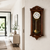 Orologio da parete in legno marrone appeso al muro con quadrante rotondo e campana dorata