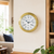 Orologio da parete con cassa rotonda in ottone, quadrante bianco e lancette blu, numeri romani.