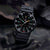 Orologio sportivo su tessuto scuro: quadrante nero con indici luminescenti e cinturino nero