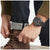 Orologio da uomo al polso con cinturino nero e quadrante scuro.