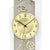 Nahaufnahme: Wanduhr mit goldenem Ziffernblatt, AMS-Logo und Rosenornamenten