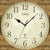 AMS Wanduhr Großaufnahme: beige Zifferblatt, schwarze Zeiger, Funkuhr-Symbol, Holzstruktur