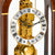 Dettaglio orologio da tavolo in legno: movimento meccanico color oro con numeri romani